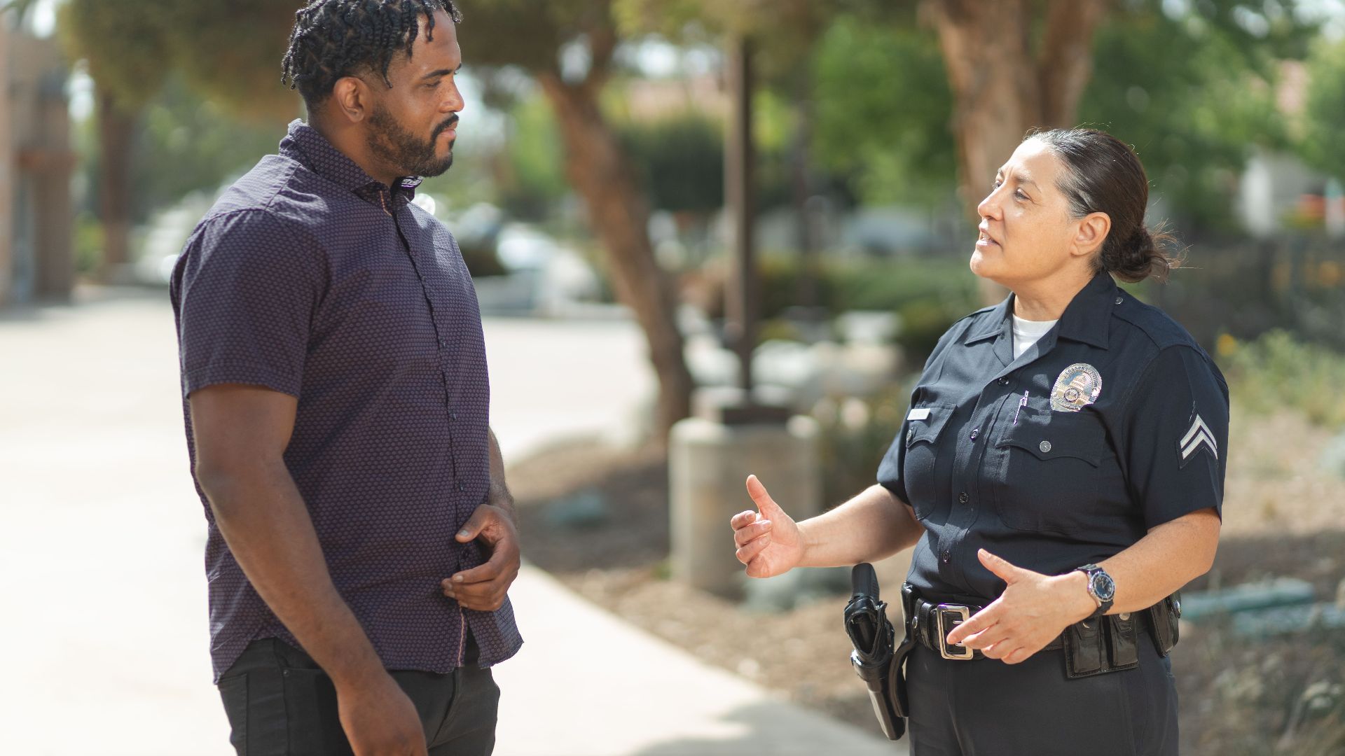 A police officer engaging warmly with a community member outdoors on a sunny day.
