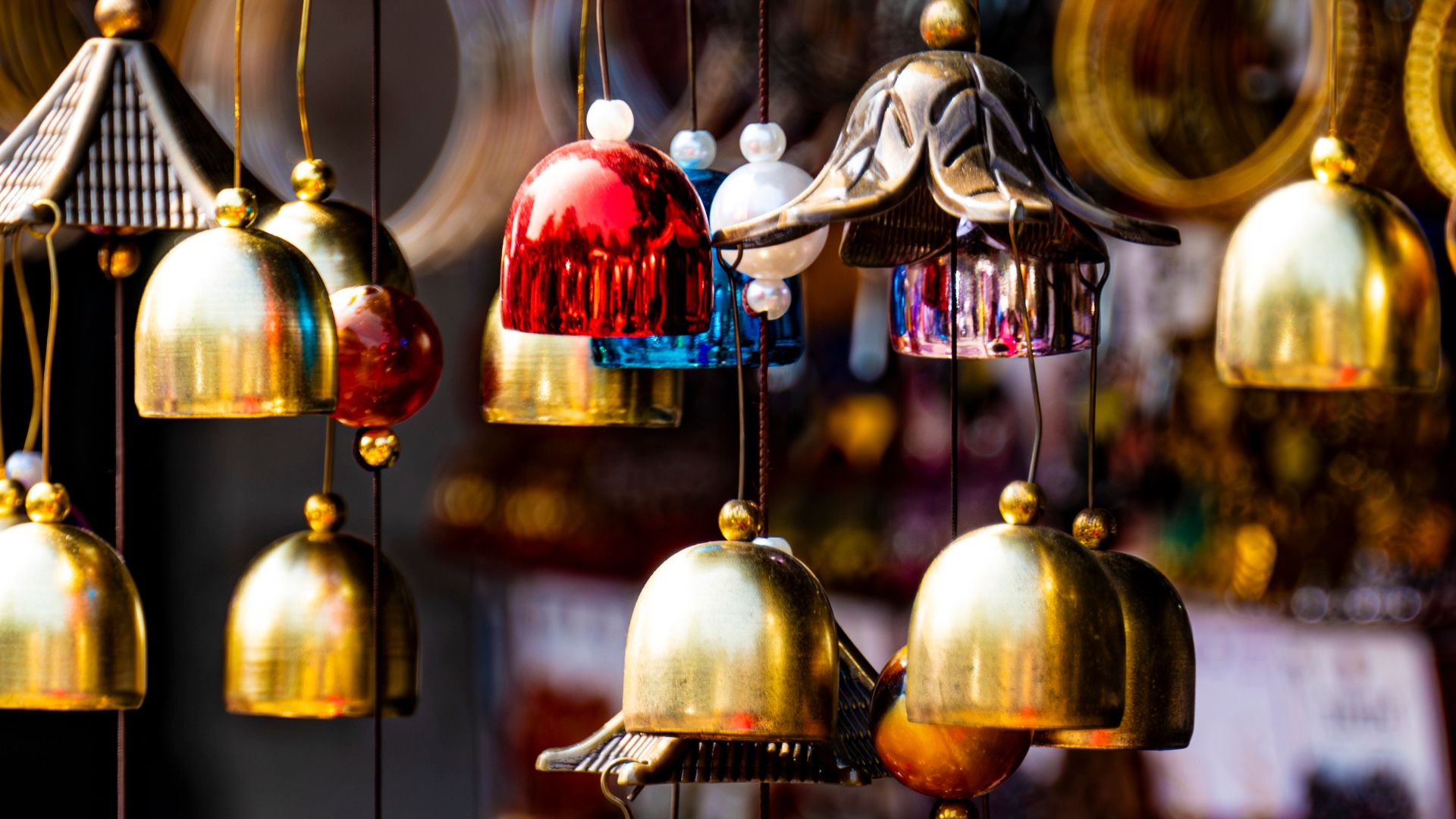 Vibrant brass wind chimes hanging in Araku Valley market, showcasing handmade craftsmanship.