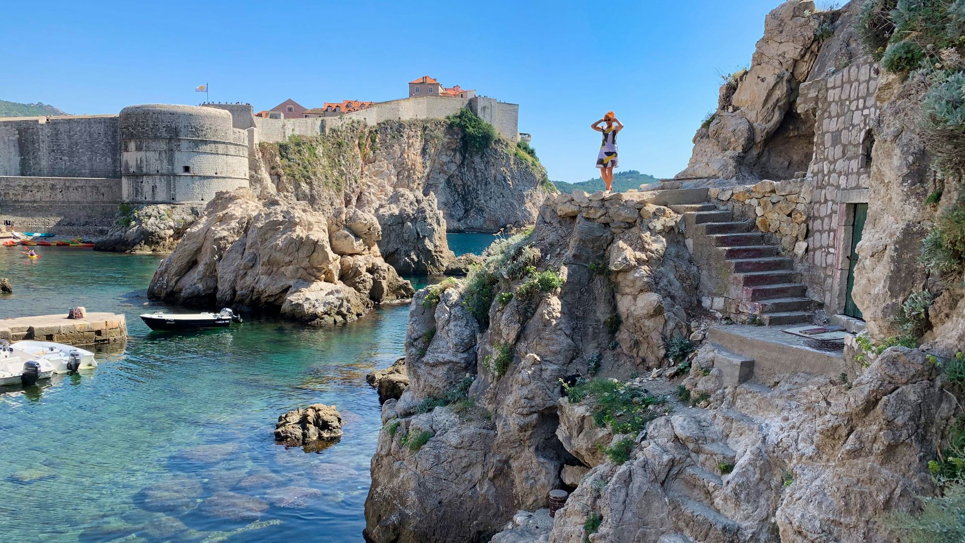 man standing on rock formation near body of water during daytime