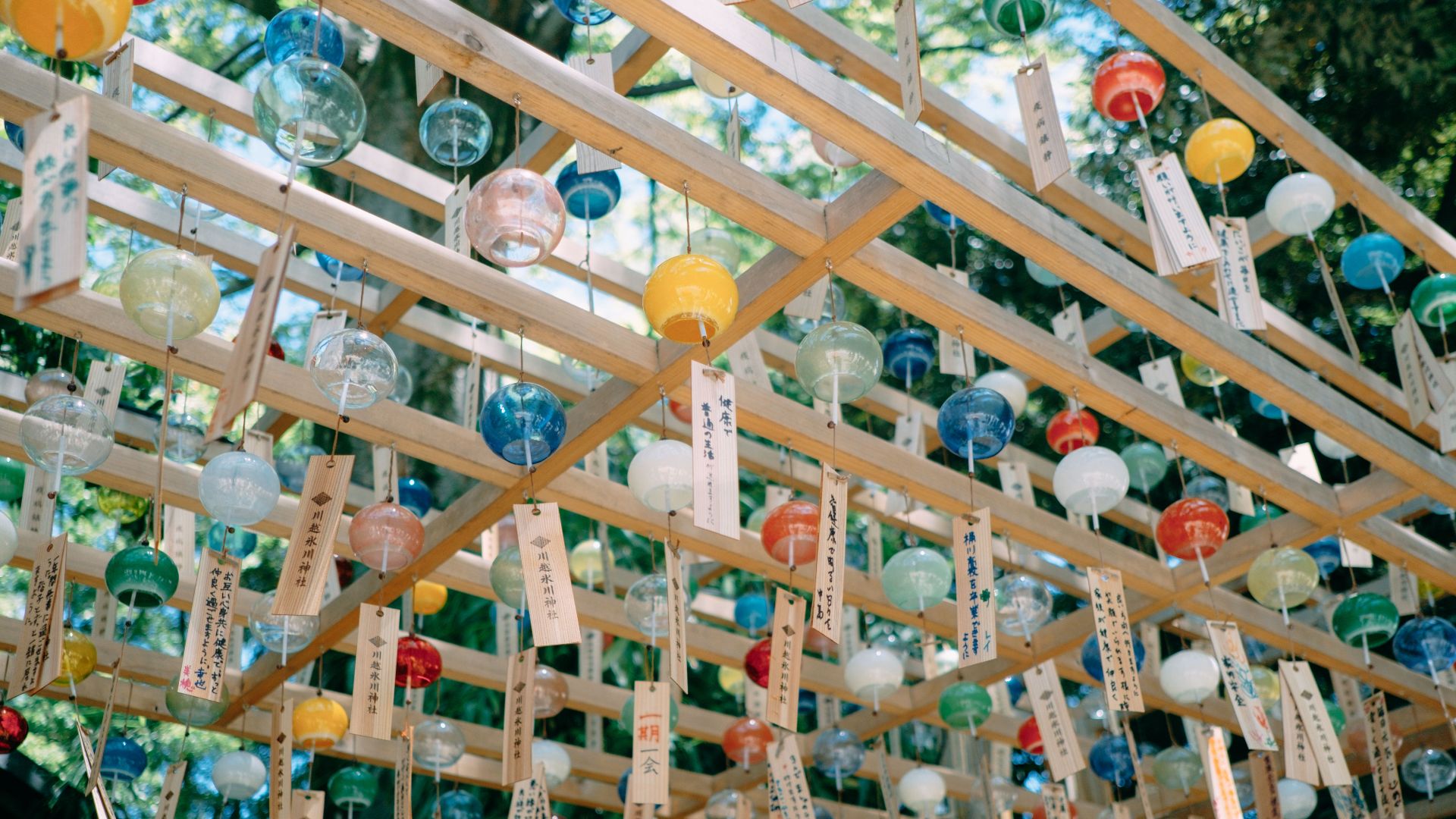 Vibrant Japanese wind chimes hanging under a wooden structure, reflecting cultural decoration.