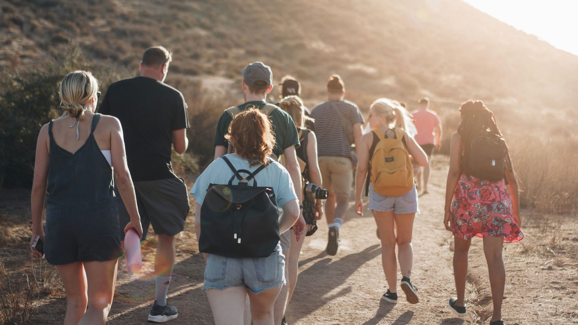 people walking on dirt road near mountain during daytime