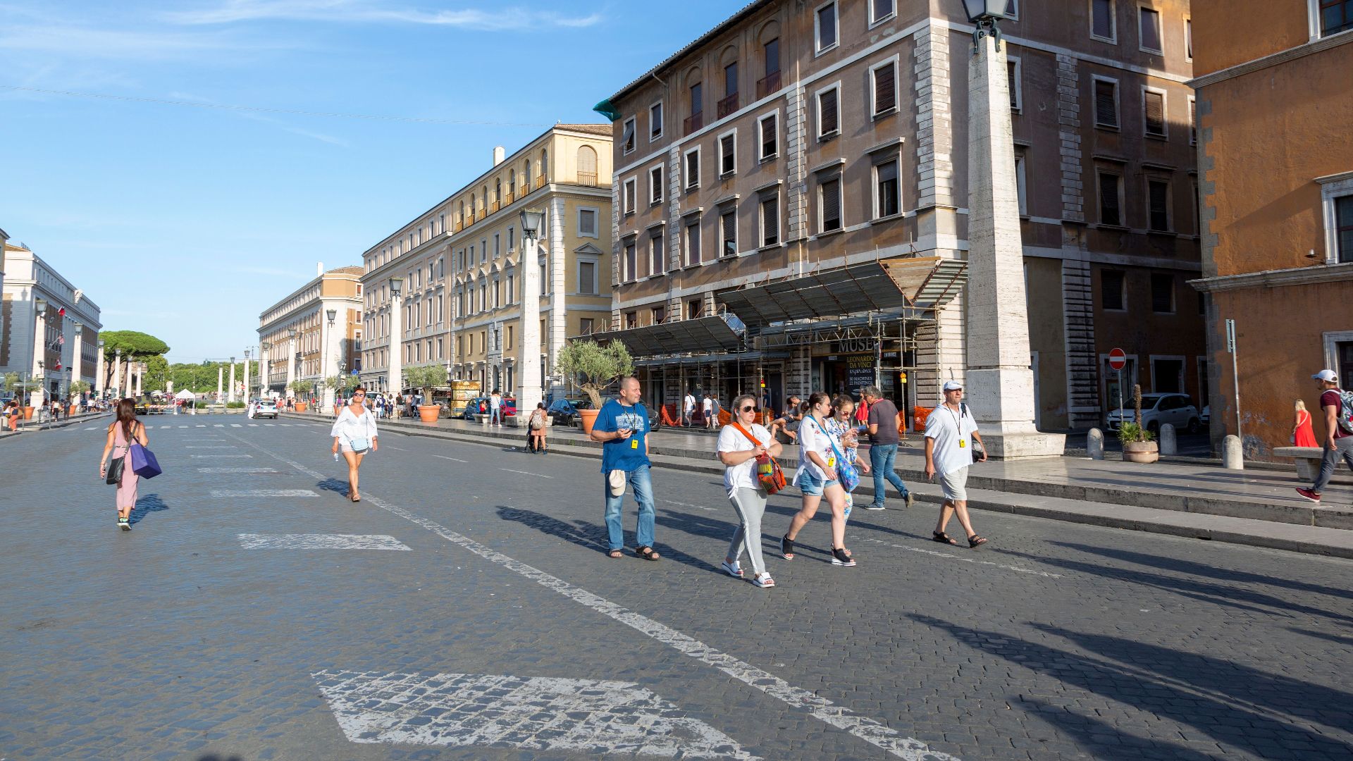 A lively street scene on Via della Conciliazione in Rome with people and historic architecture.