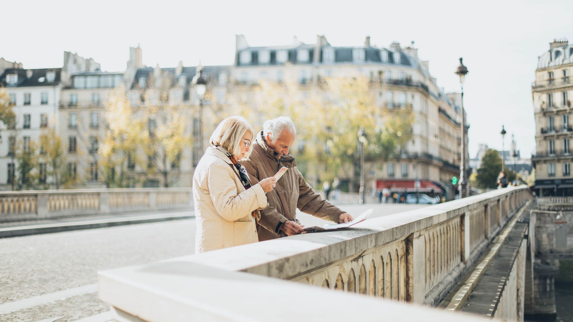 An elderly couple using a map in a scenic European city with historical architecture.
