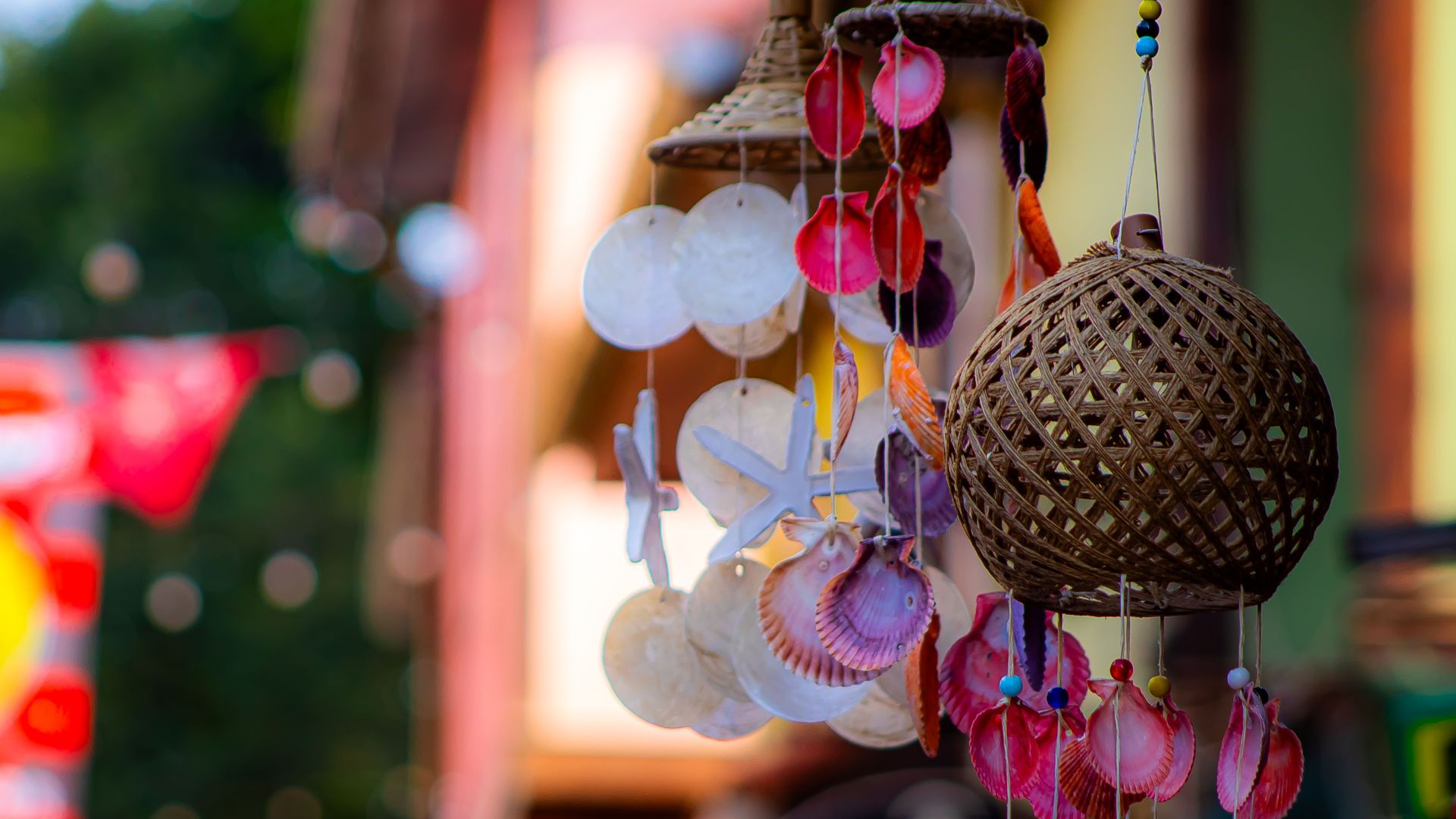Vibrant shell wind chimes in focus with blurred market street backdrop, exuding a lively and festive atmosphere.