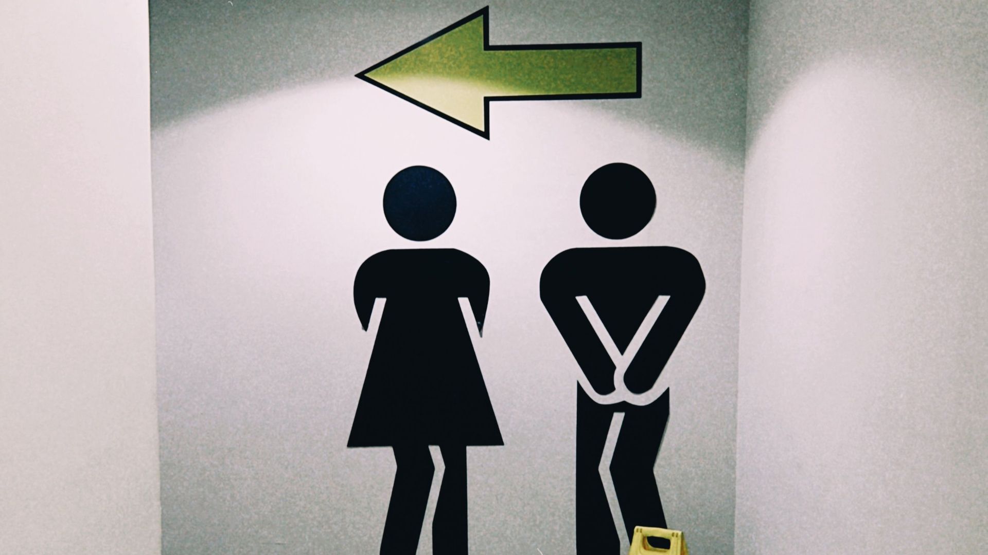 Modern restroom direction signage inside a mall in Almaty, Kazakhstan with wet floor caution sign.