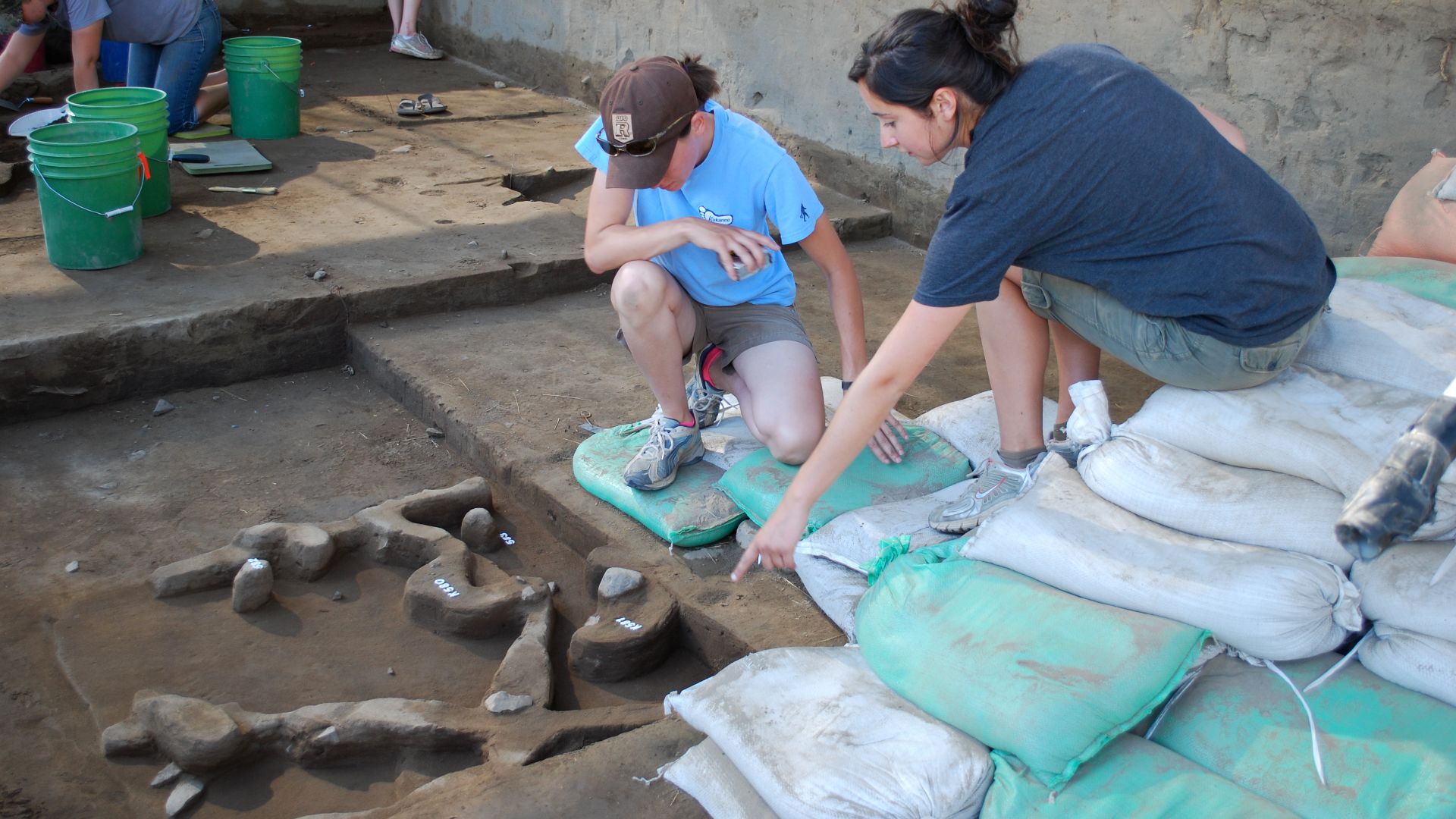 An OSU field school student shows a visitor an excavated area at Cooper's Ferry