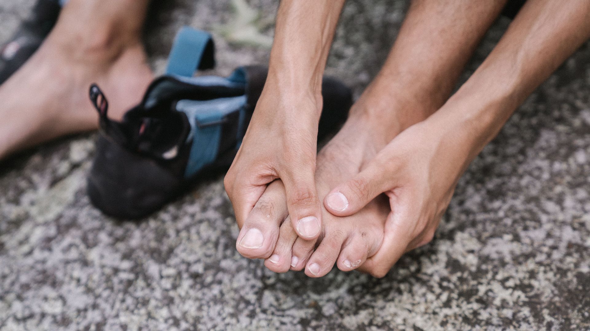 A person outdoors massaging their bare feet, conveying relaxation and care.
