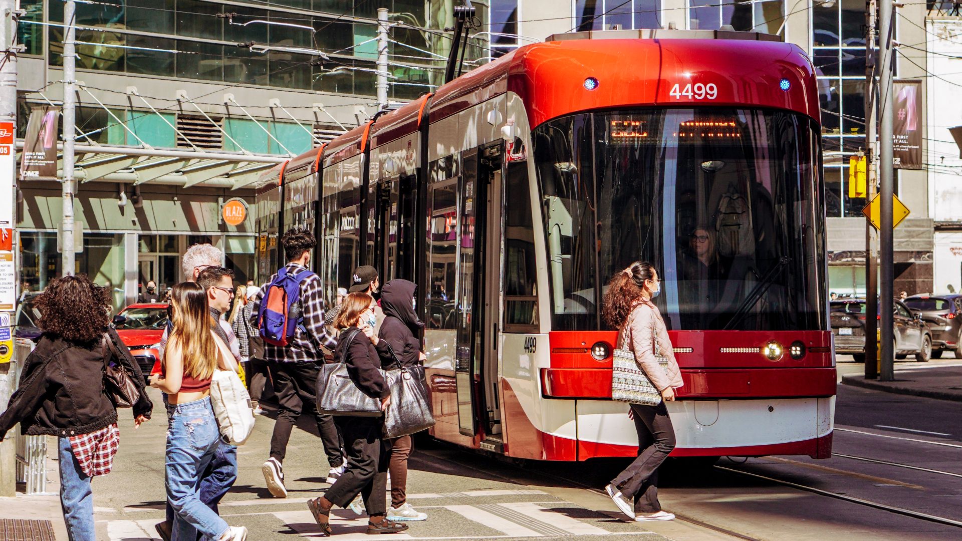Vibrant urban scene in Toronto with pedestrians and a red streetcar.