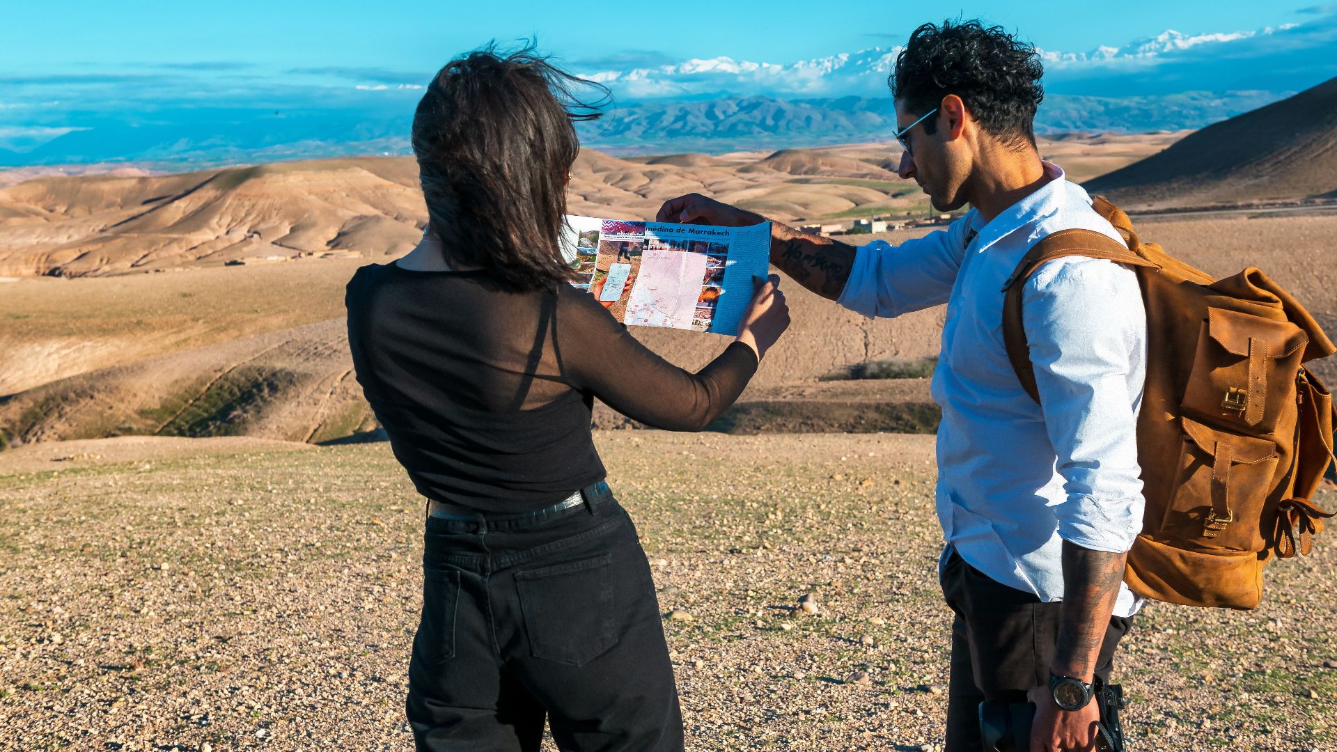 Two people examining a map in the stunning desert landscape of Marrakech-Safi, Morocco.