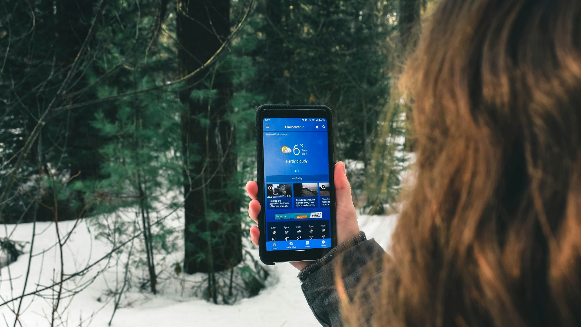 woman holding black smartphone taking photo of trees during daytime