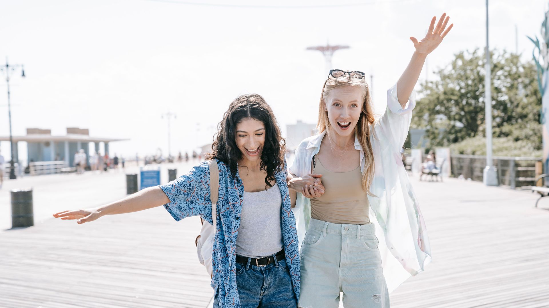 Two women having fun on a sunny boardwalk, embracing friendship and summer vibes.