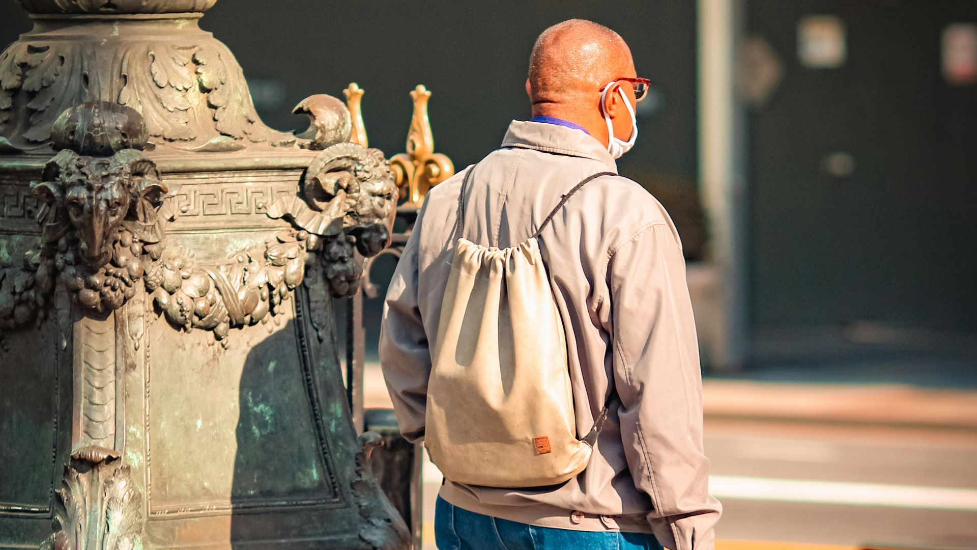 man in brown dress shirt and blue denim jeans standing near black statue during daytime