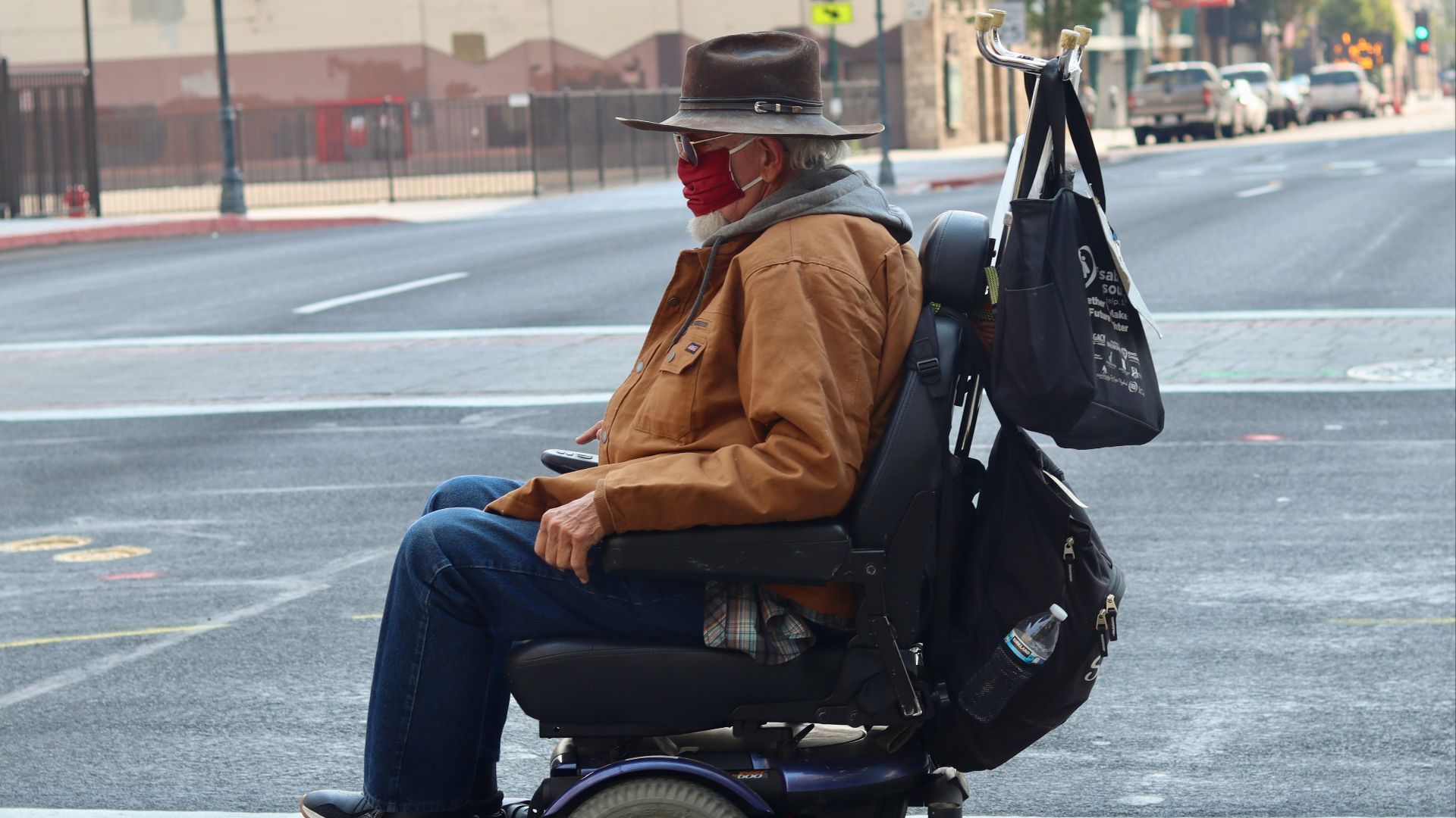 man in brown jacket and blue denim jeans sitting on black wheel chair