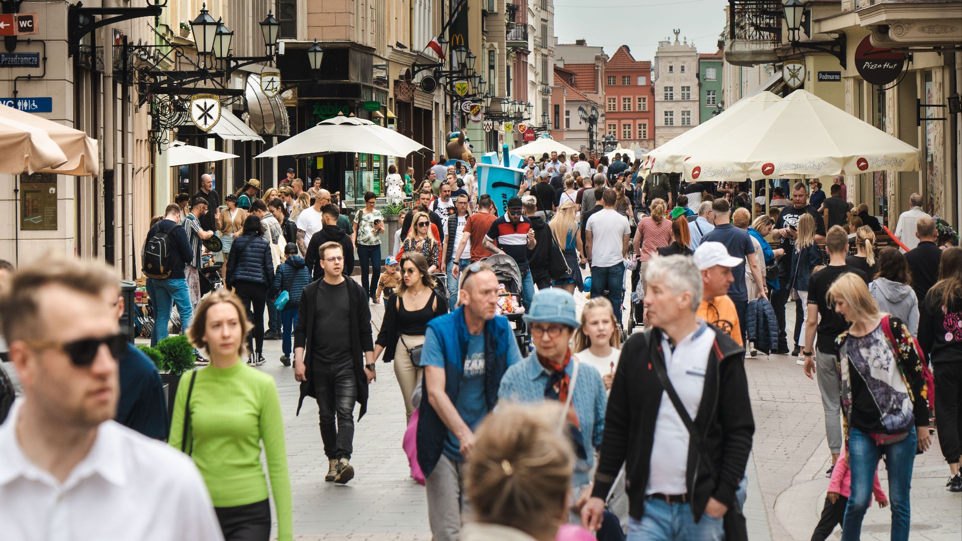 Vibrant street life in Toruń with people walking amidst historic buildings.