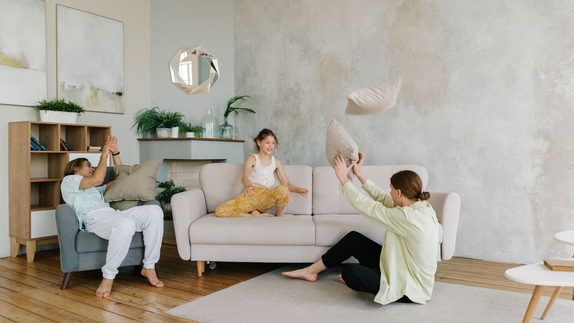 A happy family enjoying playful bonding time at home by tossing pillows in a cozy living room.