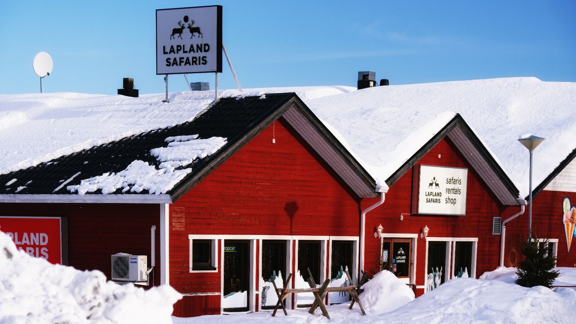 Snow-covered Lapland Safaris building in Kolari, Finland, under clear winter skies.