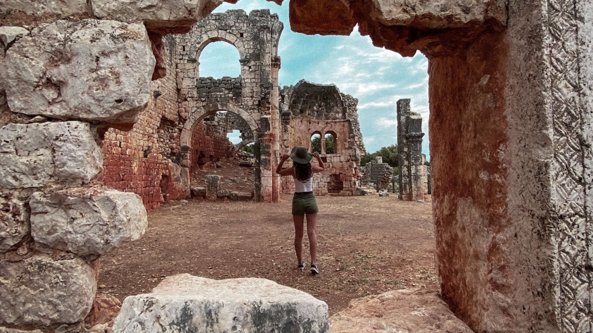 A woman photographing ancient stone ruins in Mersin, Türkiye.