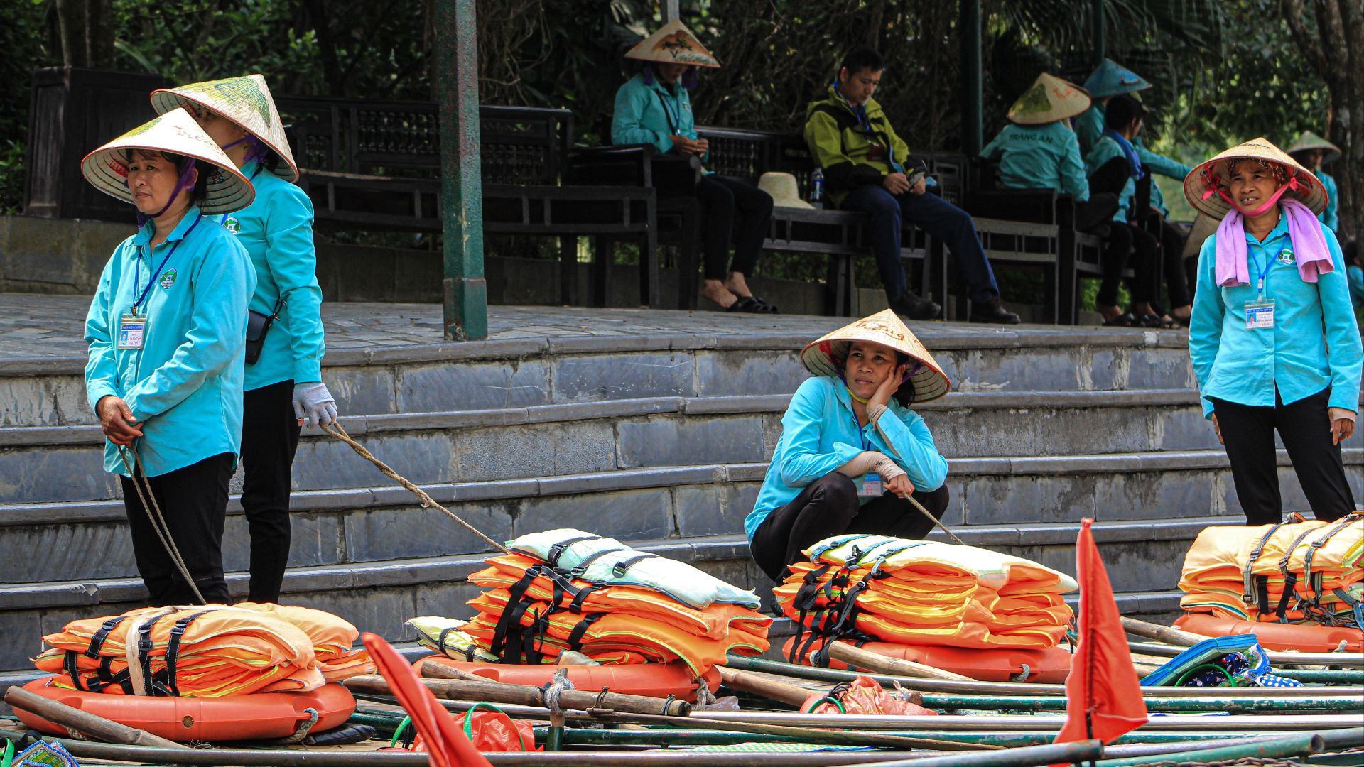 Vietnamese rowers in traditional hats preparing boats for a river tour.