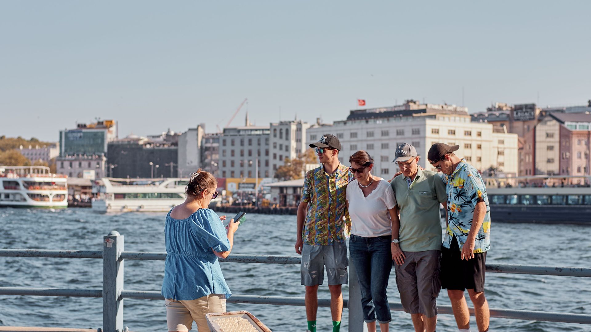 A family poses for a photo by the Bosphorus in İstanbul, capturing a memorable moment.