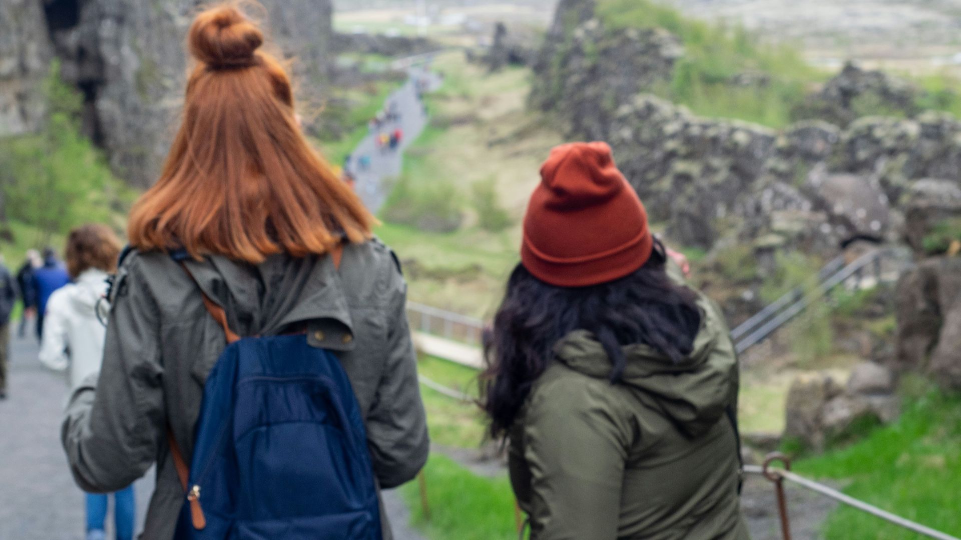 two women with backpacks walking up a hill