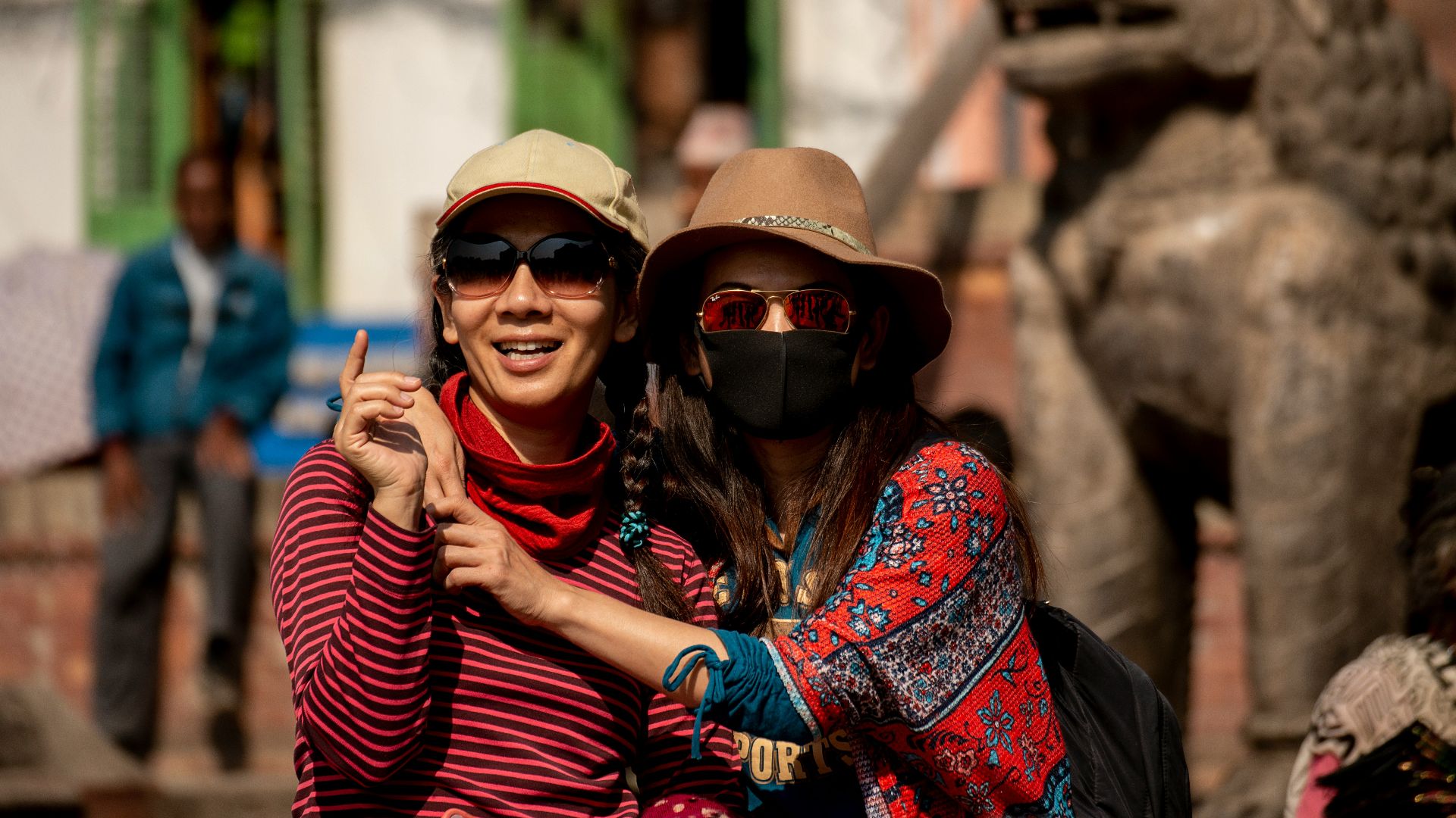 woman hugging woman while pointing and smiling during daytime