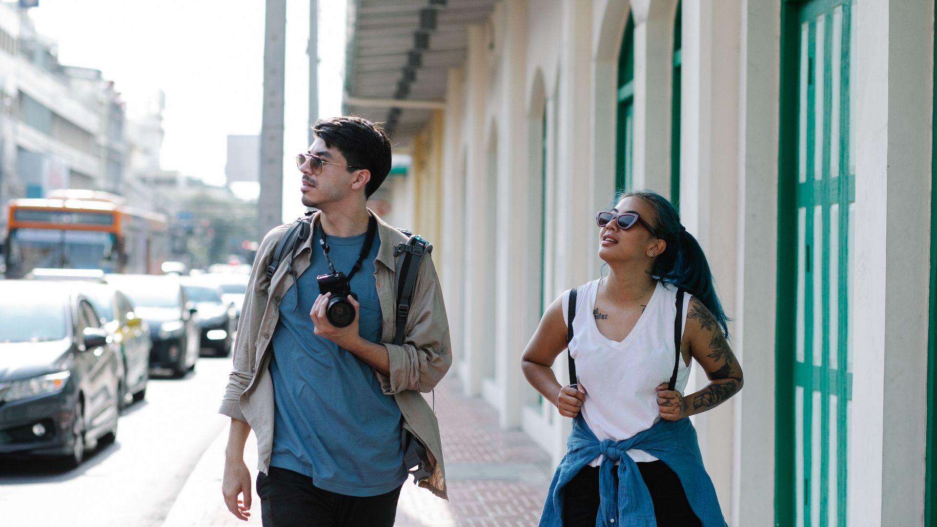 Two young tourists explore a vibrant city street, capturing memories.
