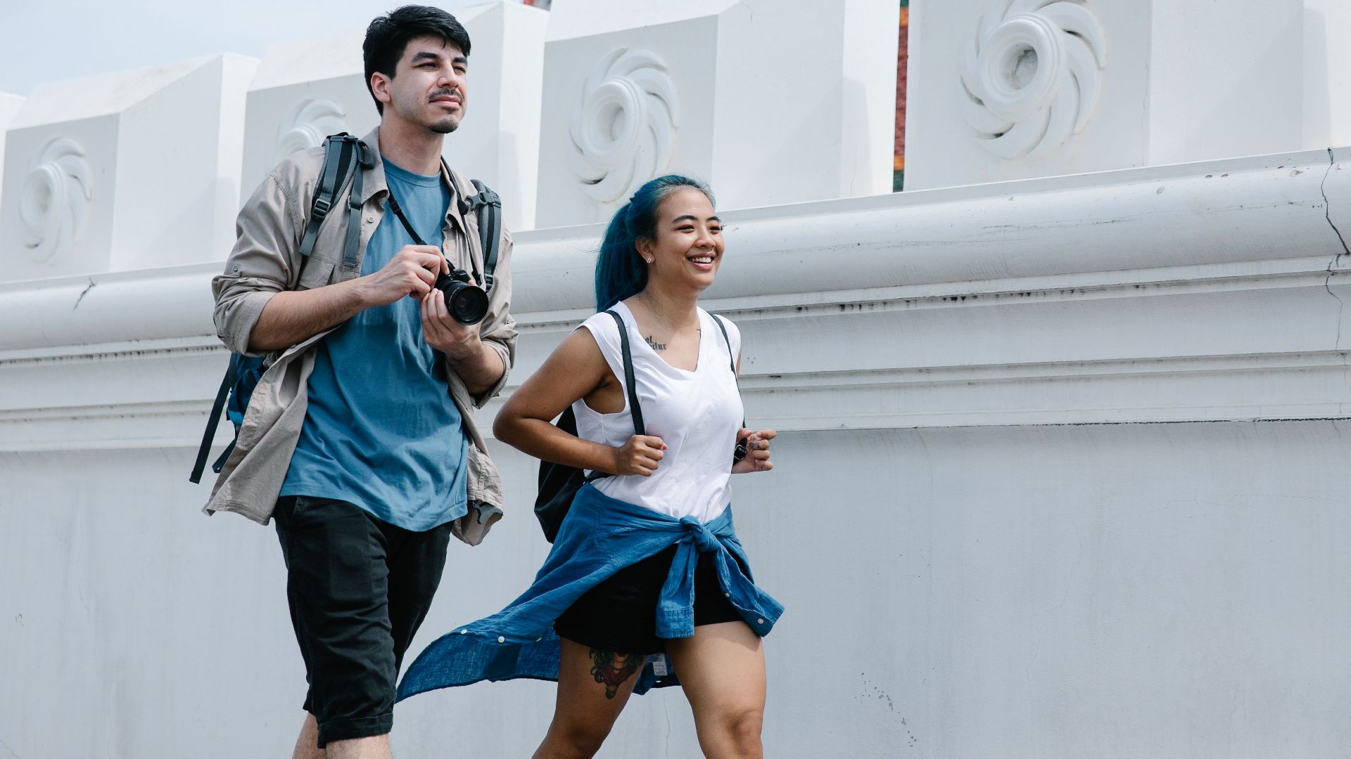 A cheerful couple exploring an outdoor landmark with traditional architecture.