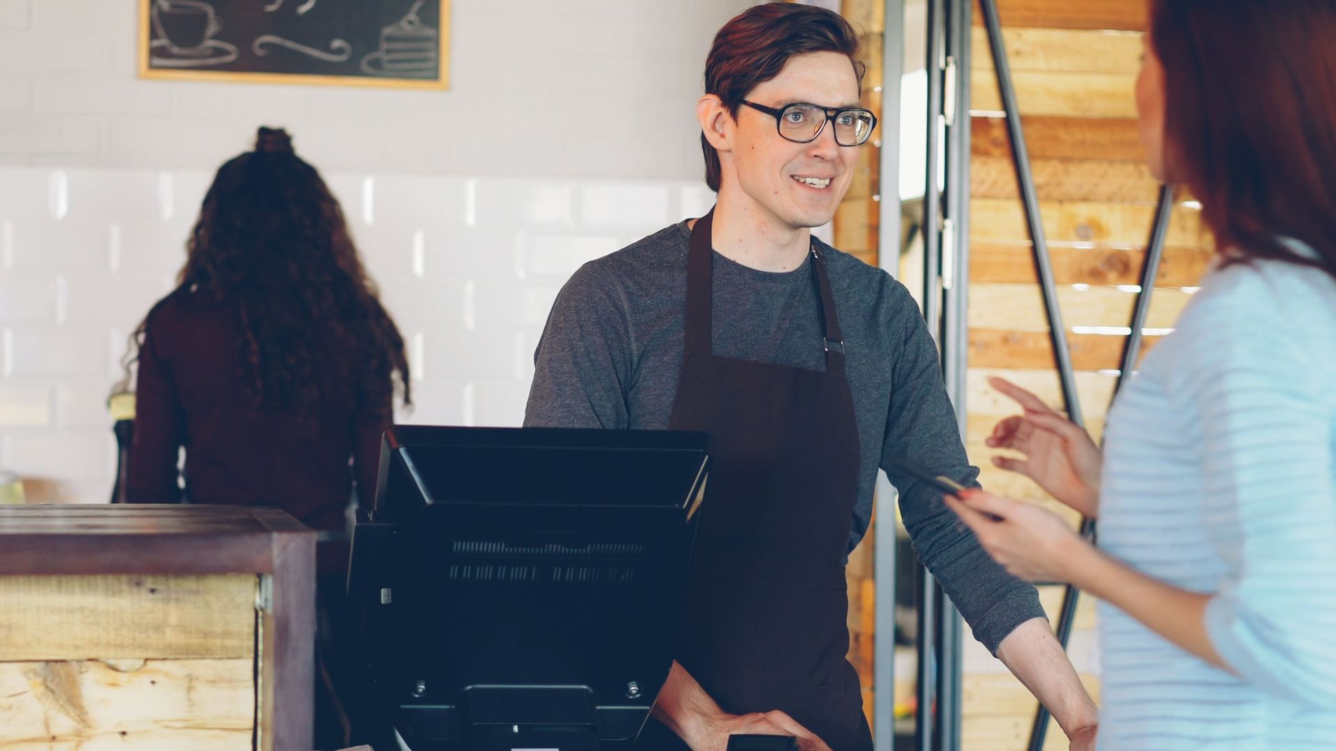 Warm interaction between barista and customer in a cozy coffee shop.