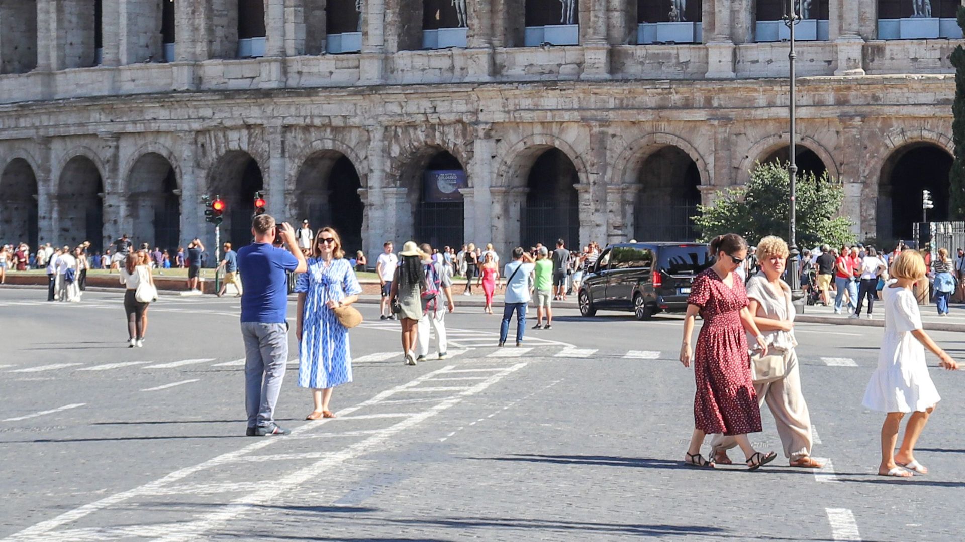 The Colosseum with tourists in Rome on a bright summer day, showcasing its historical grandeur.