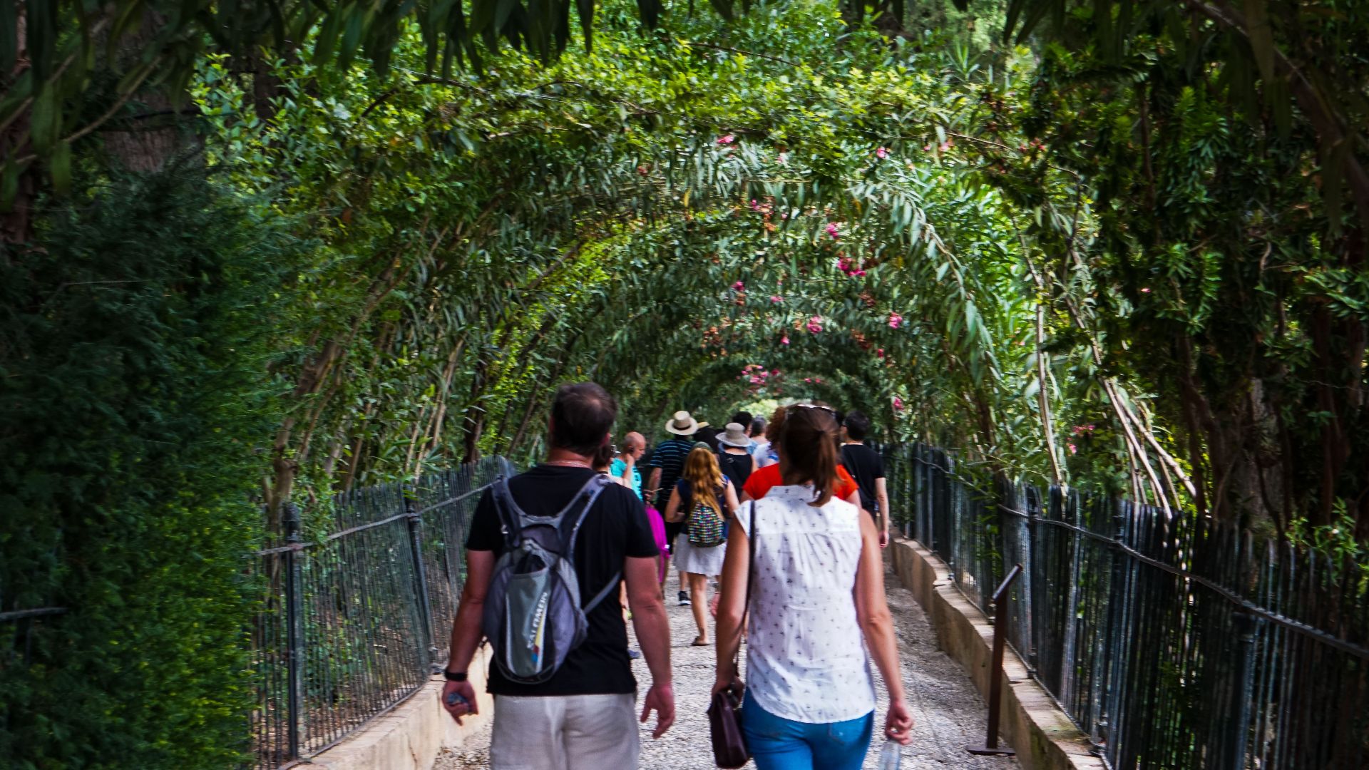 Tourists enjoy a walk through the lush, green arches in Granada, Andalusia, Spain.