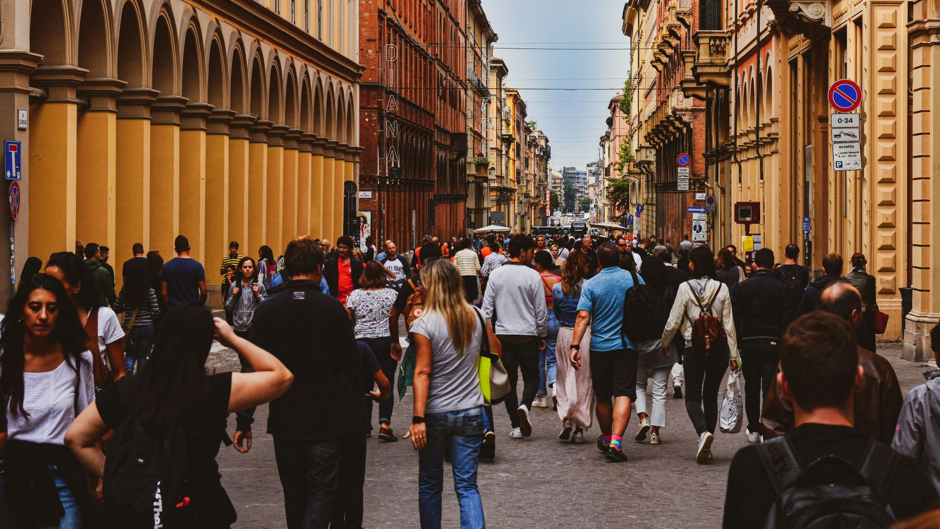 a group of people walking down a street next to tall buildings