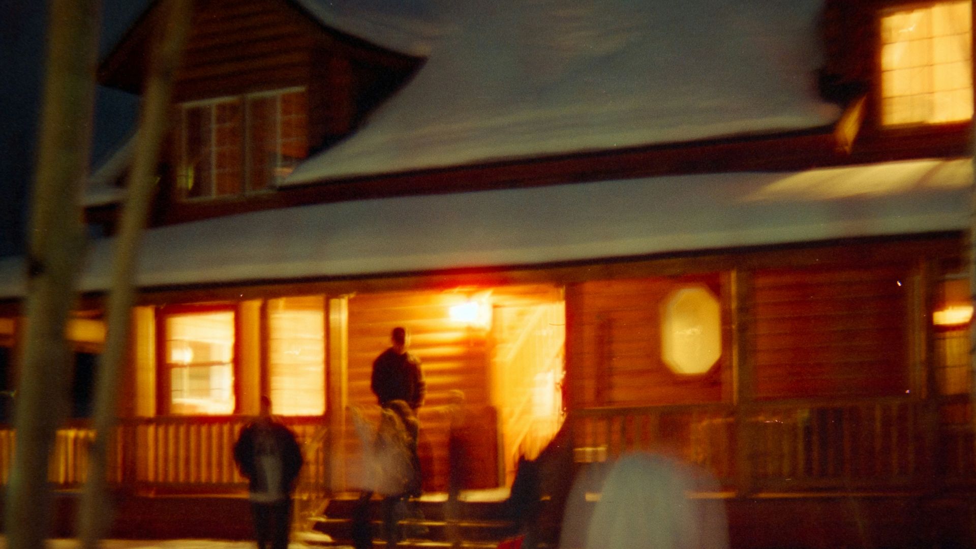 People gathered outside a log cabin at night