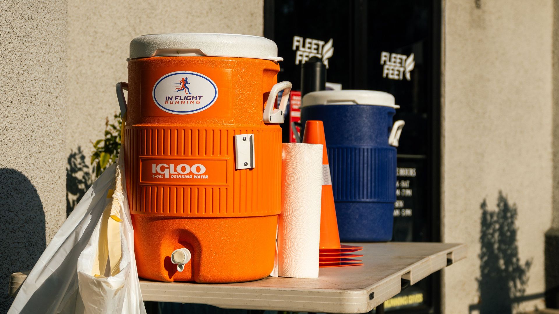 Bright outdoor scene with orange and blue water coolers at Fleet Feet store in Houston, TX.