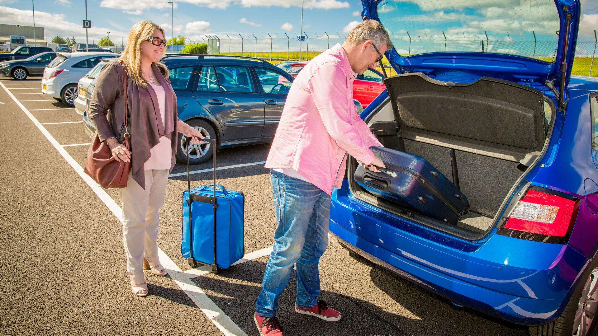 Couple loading luggage into a blue car