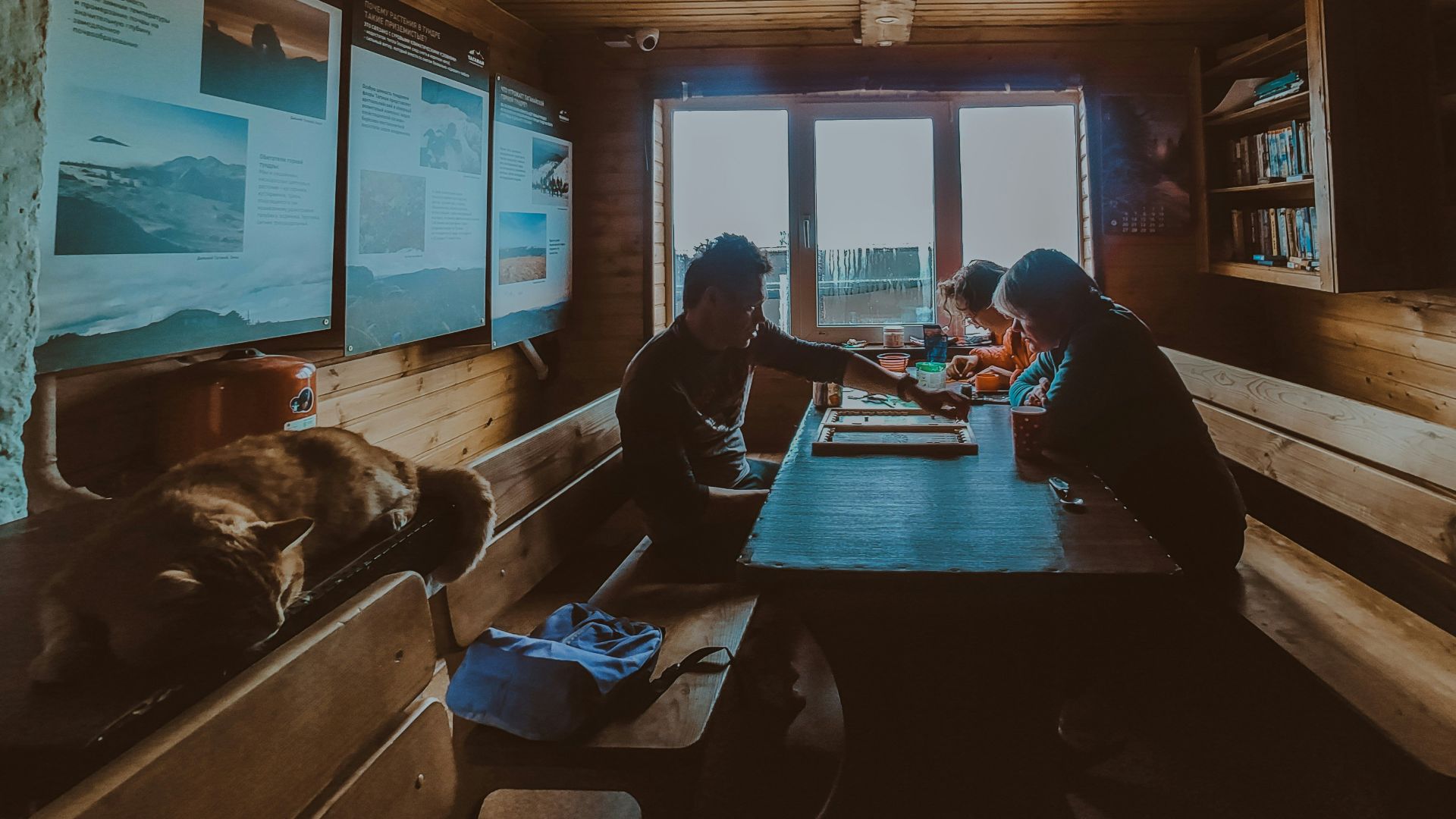 People sitting at a wooden table inside a rustic cabin.
