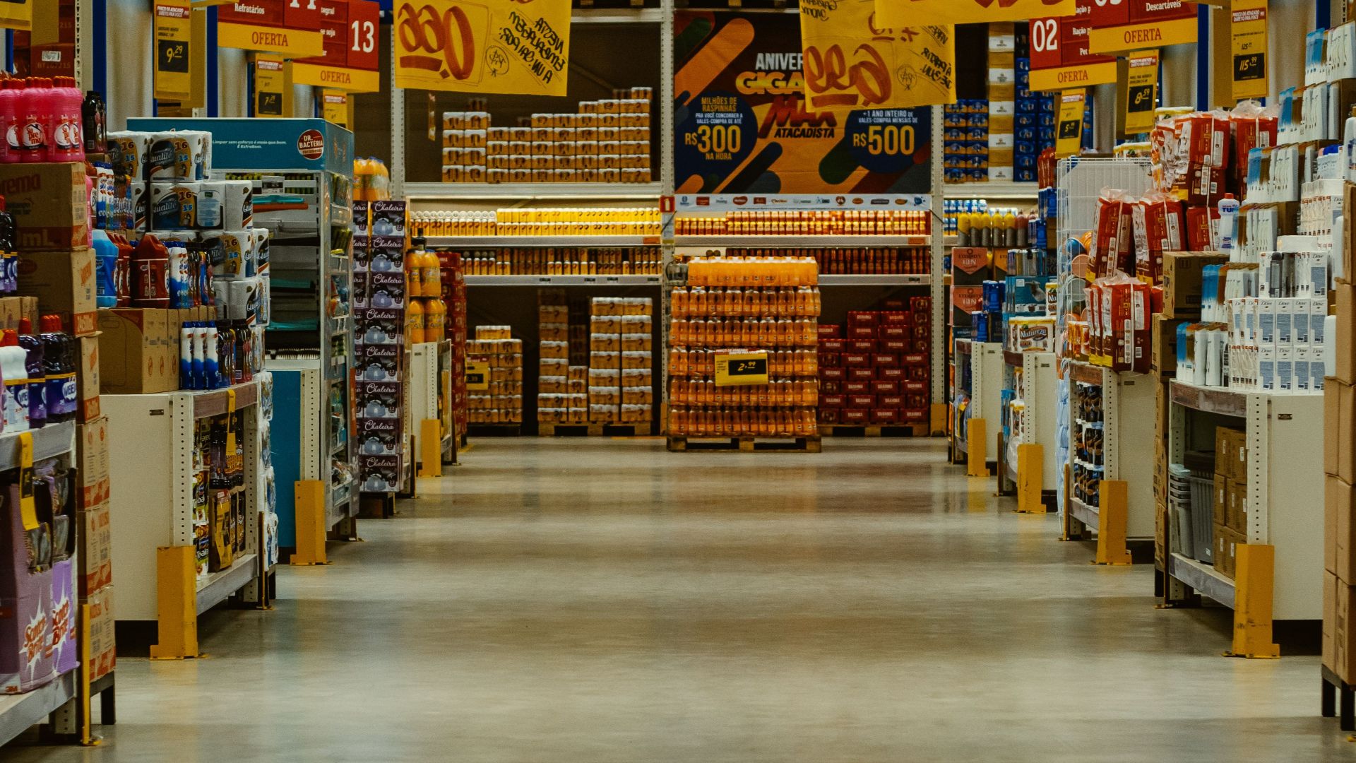 Wide supermarket aisle with colorful sale banners and stocked shelves in a vibrant Brazilian store.