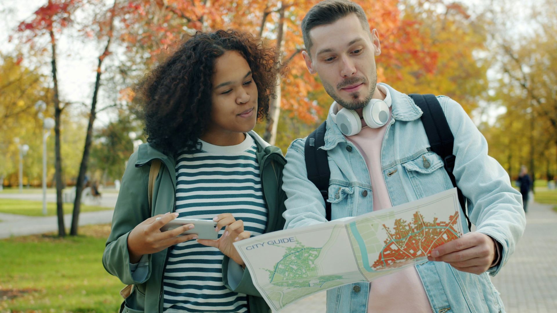 Couple looking at map in park during autumn