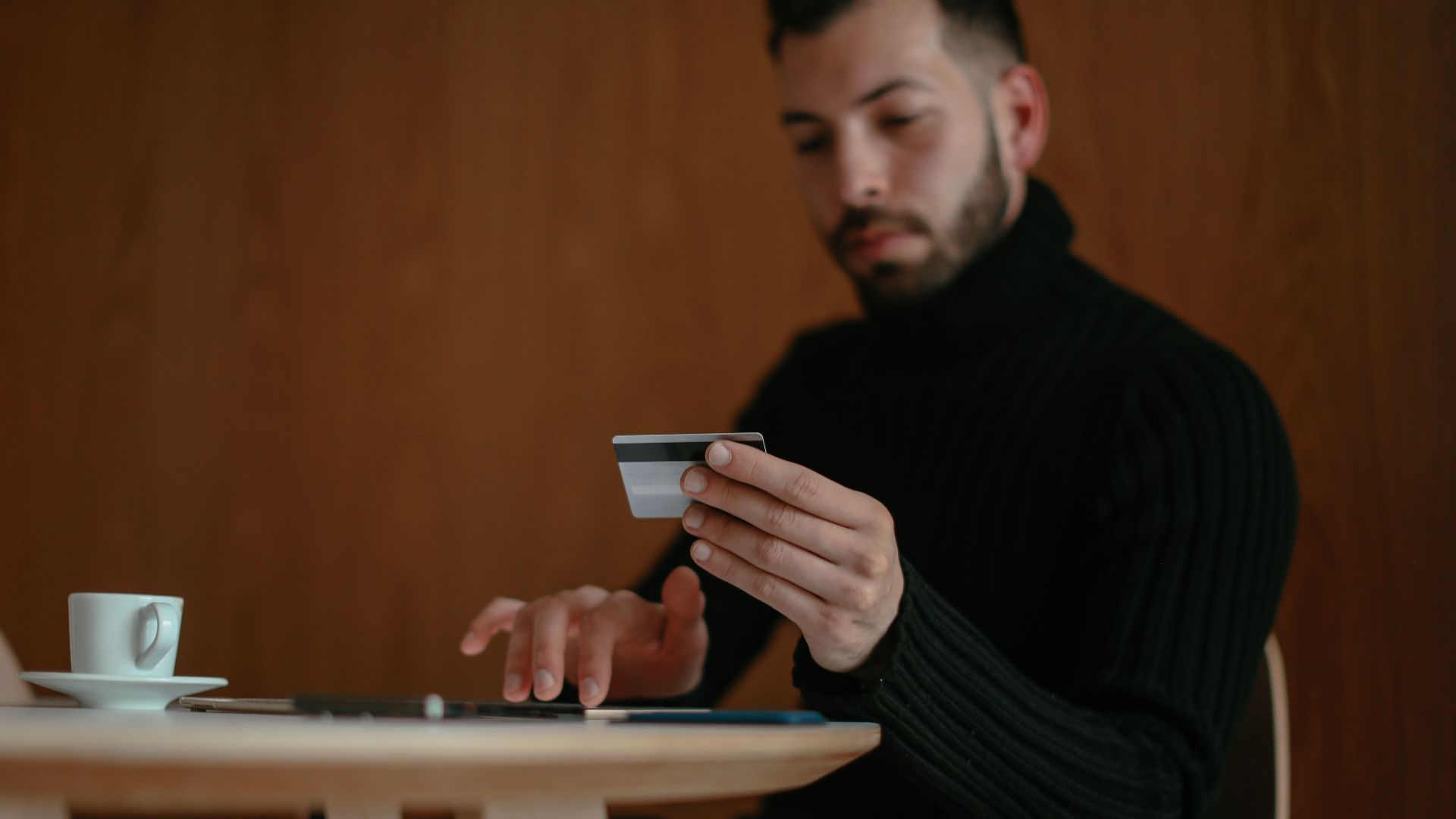Focused man in café using tablet and credit card for online shopping.
