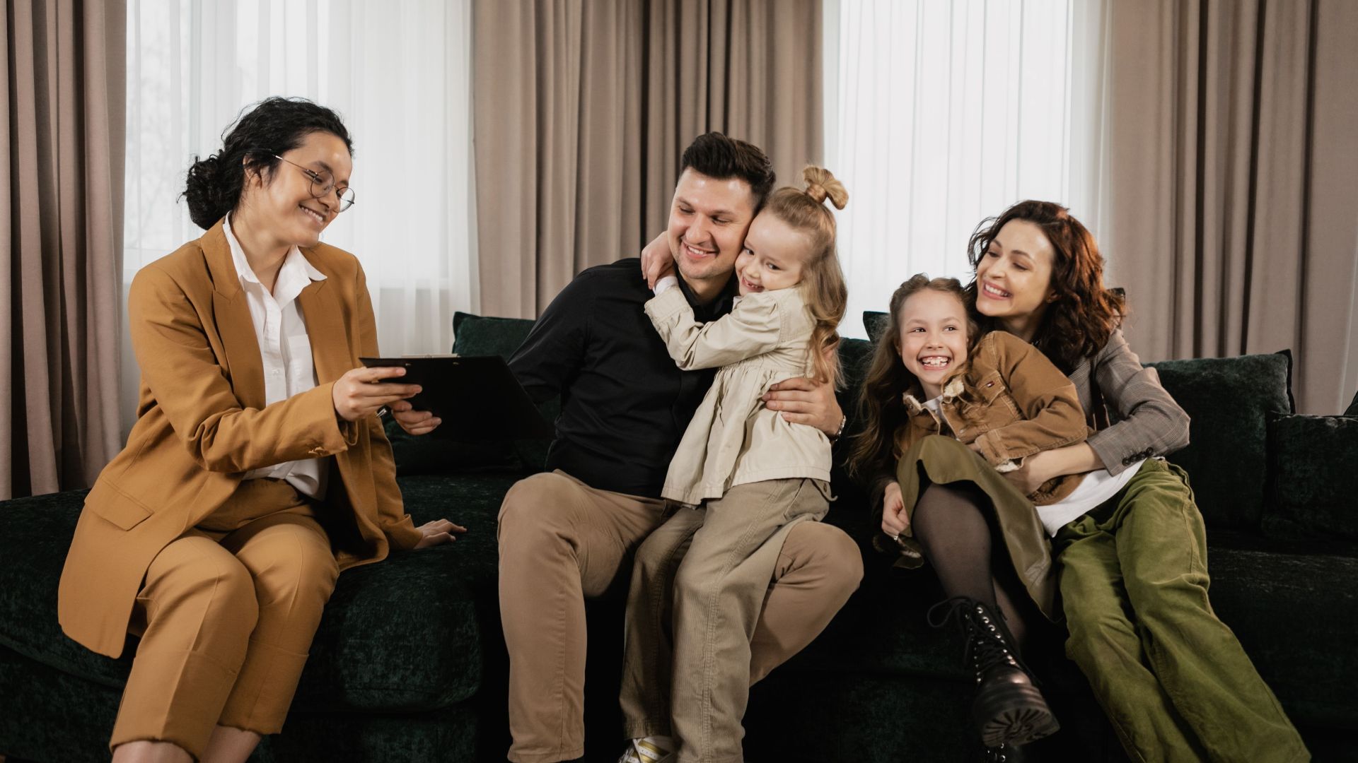 A cheerful family sitting in the living room with a real estate agent discussing a new home purchase.