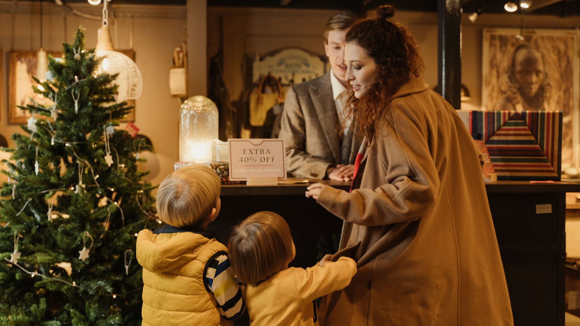 Family enjoying holiday shopping at a decorated store with a Christmas tree and sale offer.