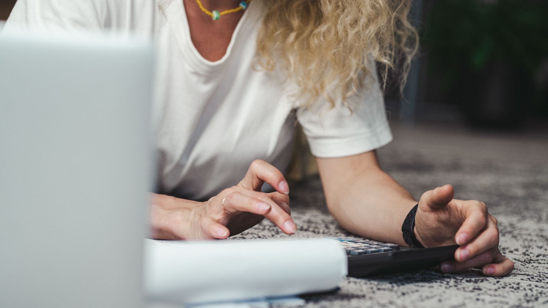 A woman engages in budget planning using a calculator on a comfortable carpeted floor.
