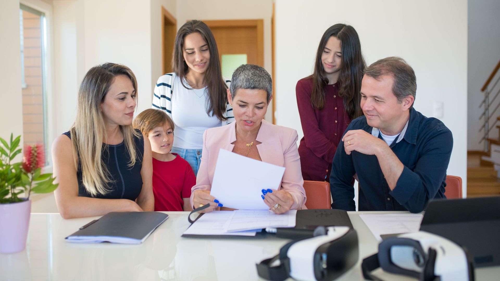 A family meeting with a female realtor reviewing documents in a bright, modern room.