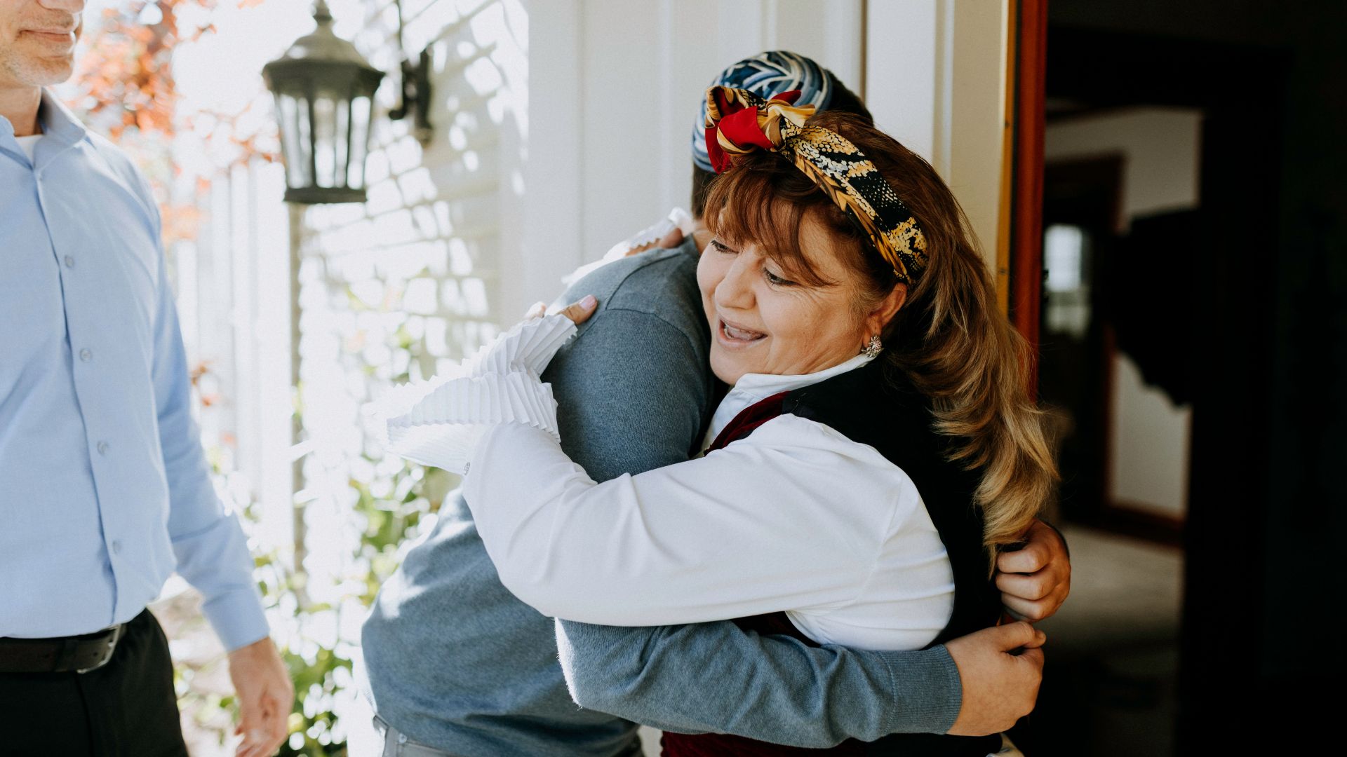 Joyful family reunion captured in a heartfelt embrace on a sunny day.
