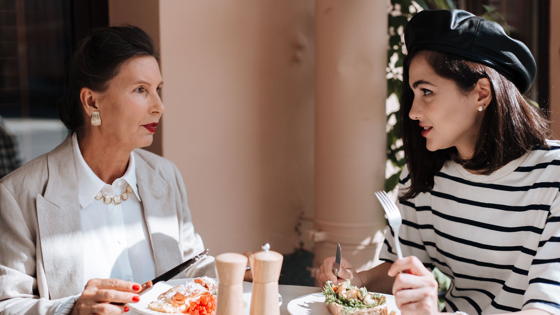 Elegant women enjoying a meal at an outdoor cafe. Fashionable style and serene atmosphere.