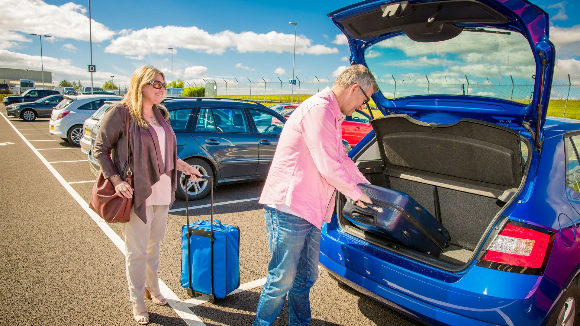 Couple loading luggage into a blue car