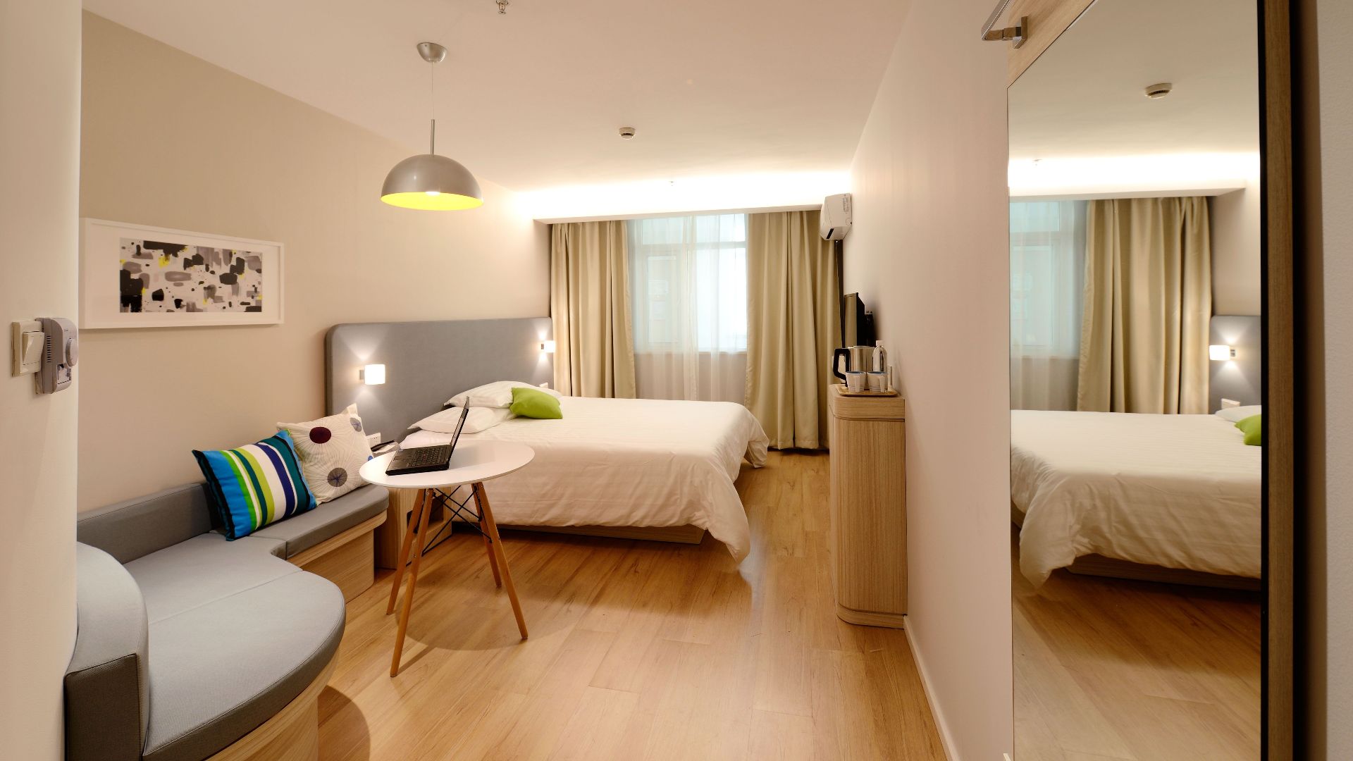 Spacious modern hotel room featuring cozy decor and neutral tones with natural light.