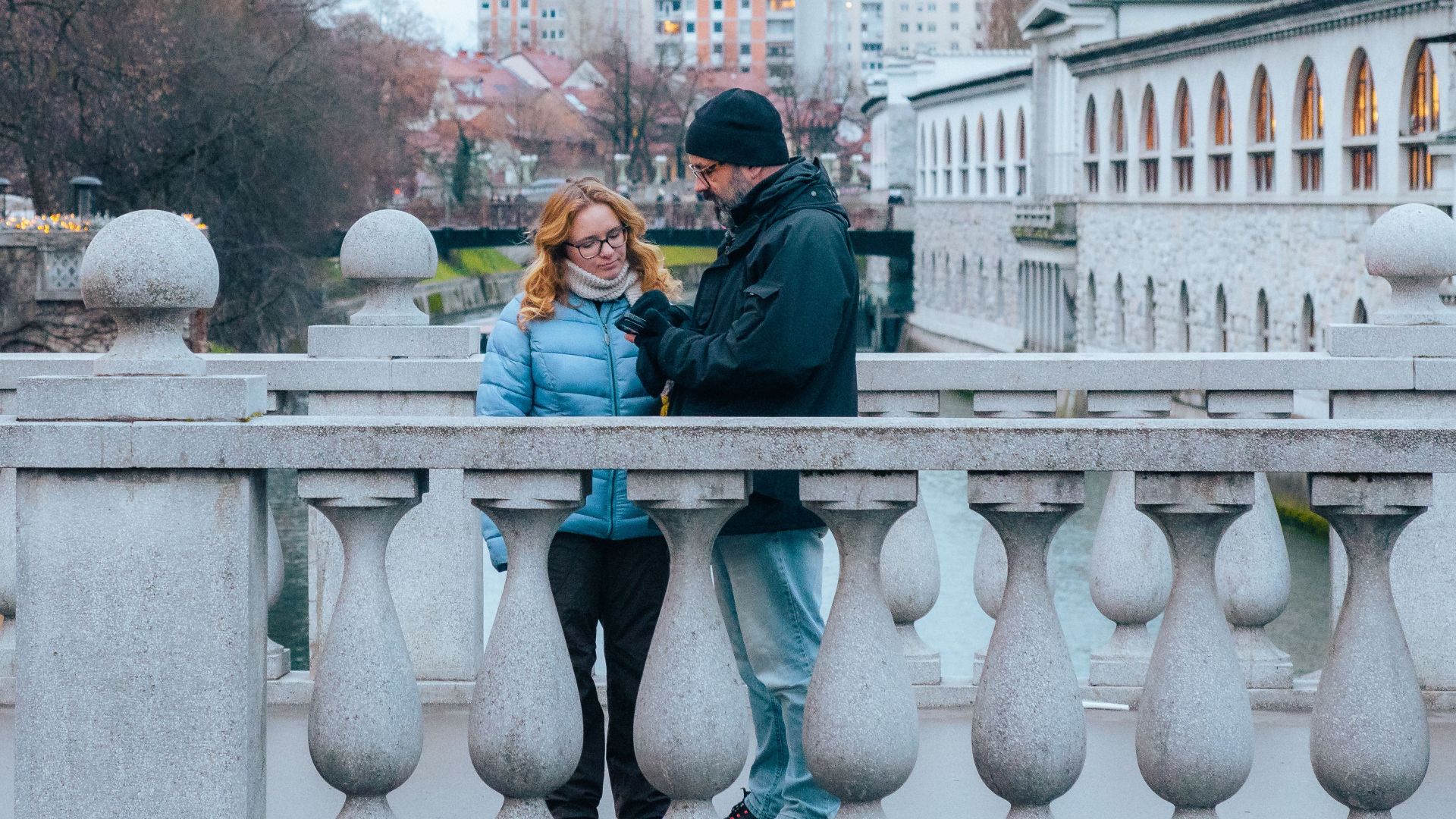 A couple converses on a bridge during a winter day in Ljubljana, Slovenia.