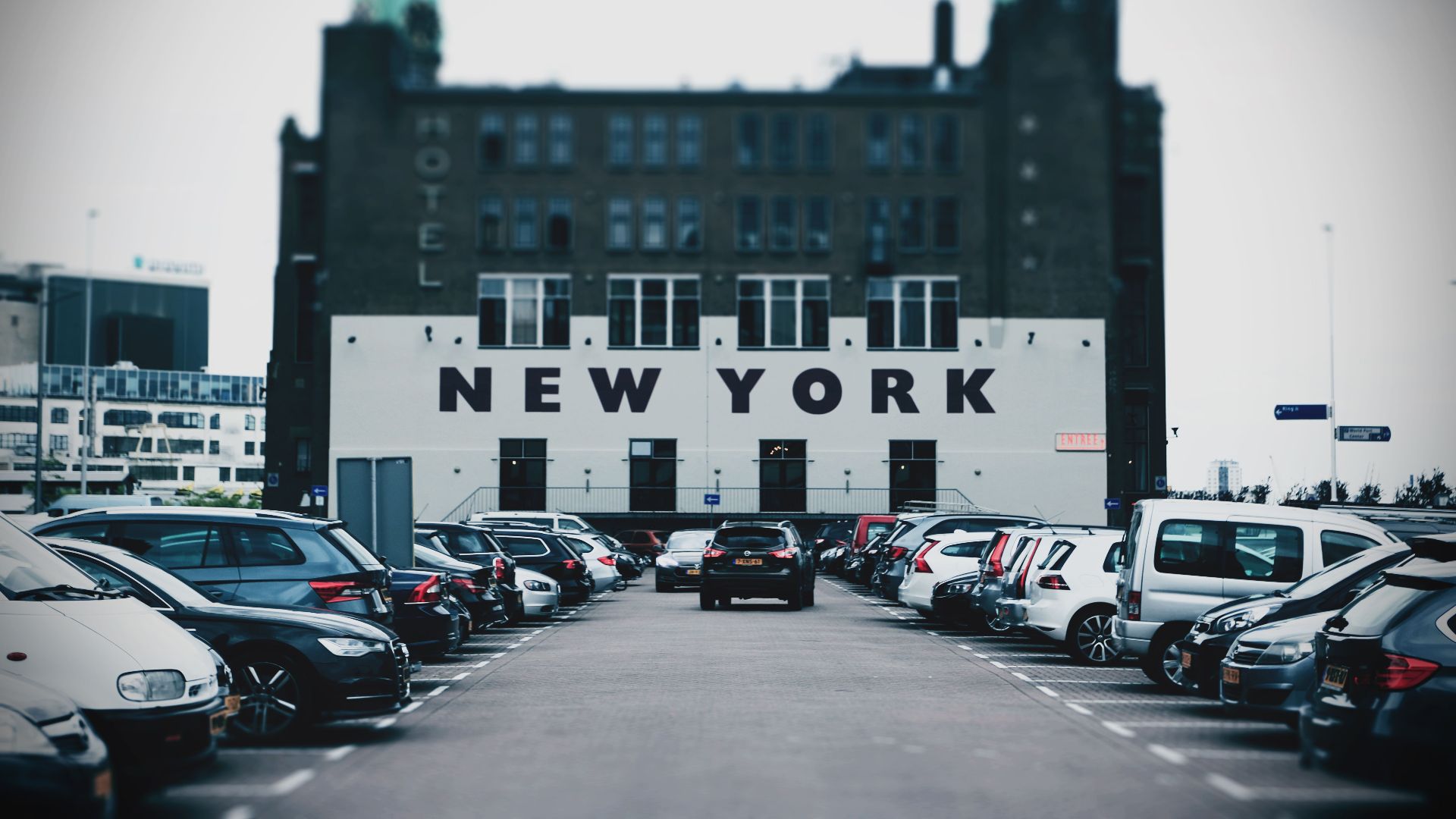 View of a parking lot with cars and a building featuring bold New York text.