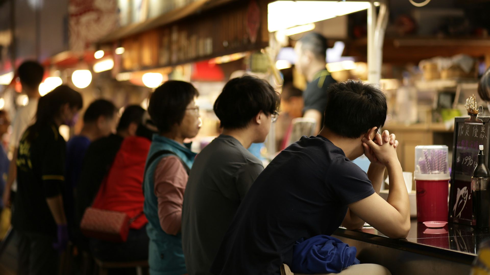 People sitting at a bar in a busy market