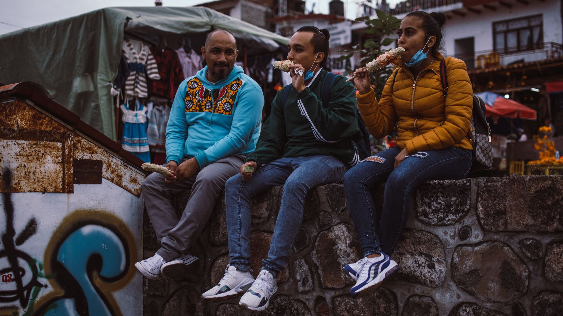 A candid capture of three people enjoying street food on a stone wall in Janitzio, Michoacán.